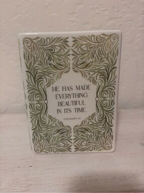 ceramic book vase with green floral swirls and the words…